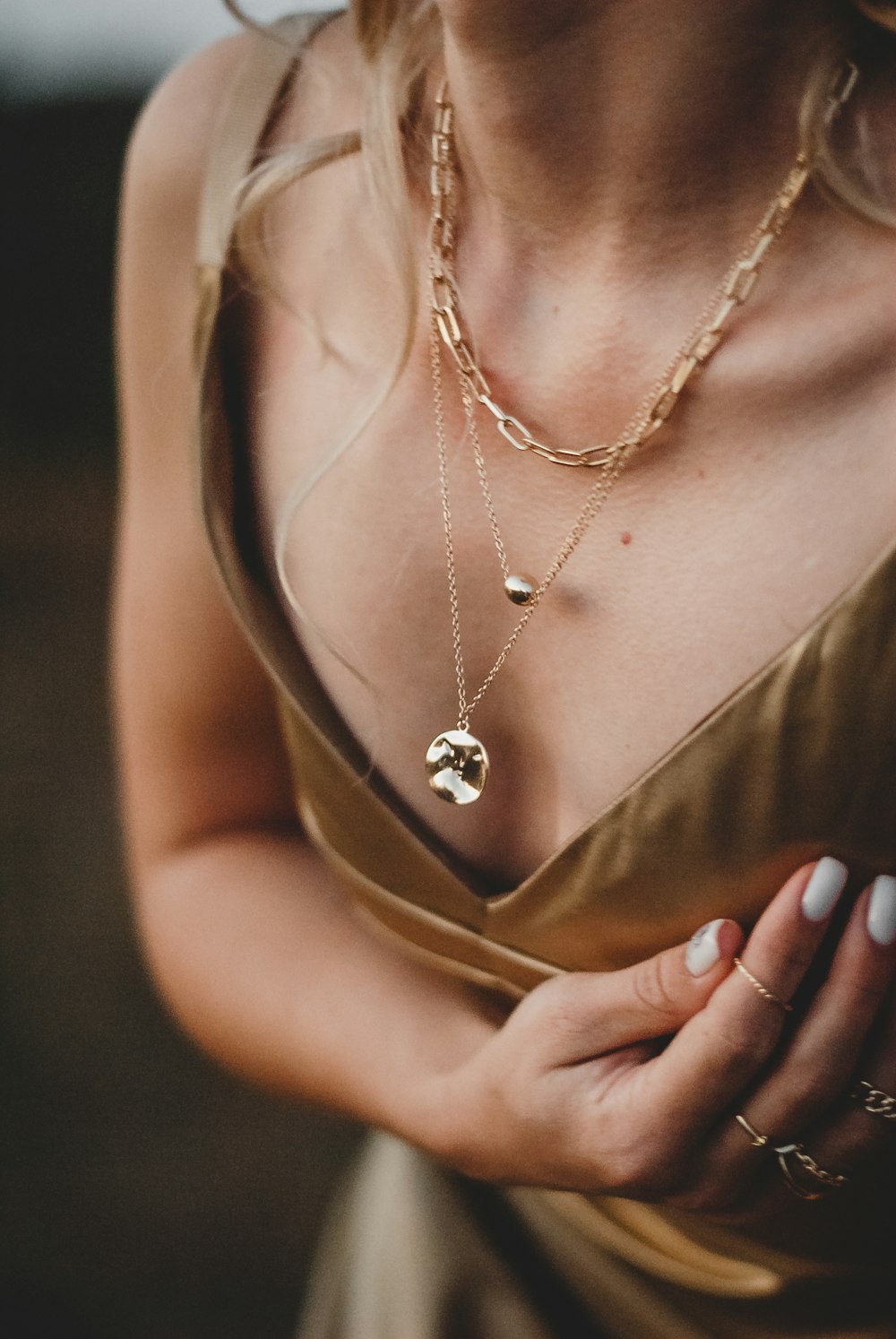 Mujer en vestido dorado sin mangas con collar de oro