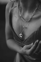 Elegant lifestyle image of a woman gently touching her neck, showcasing layered jewelry.