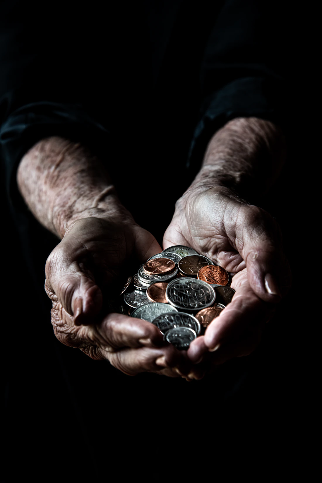 A hand holding a few silver coins
