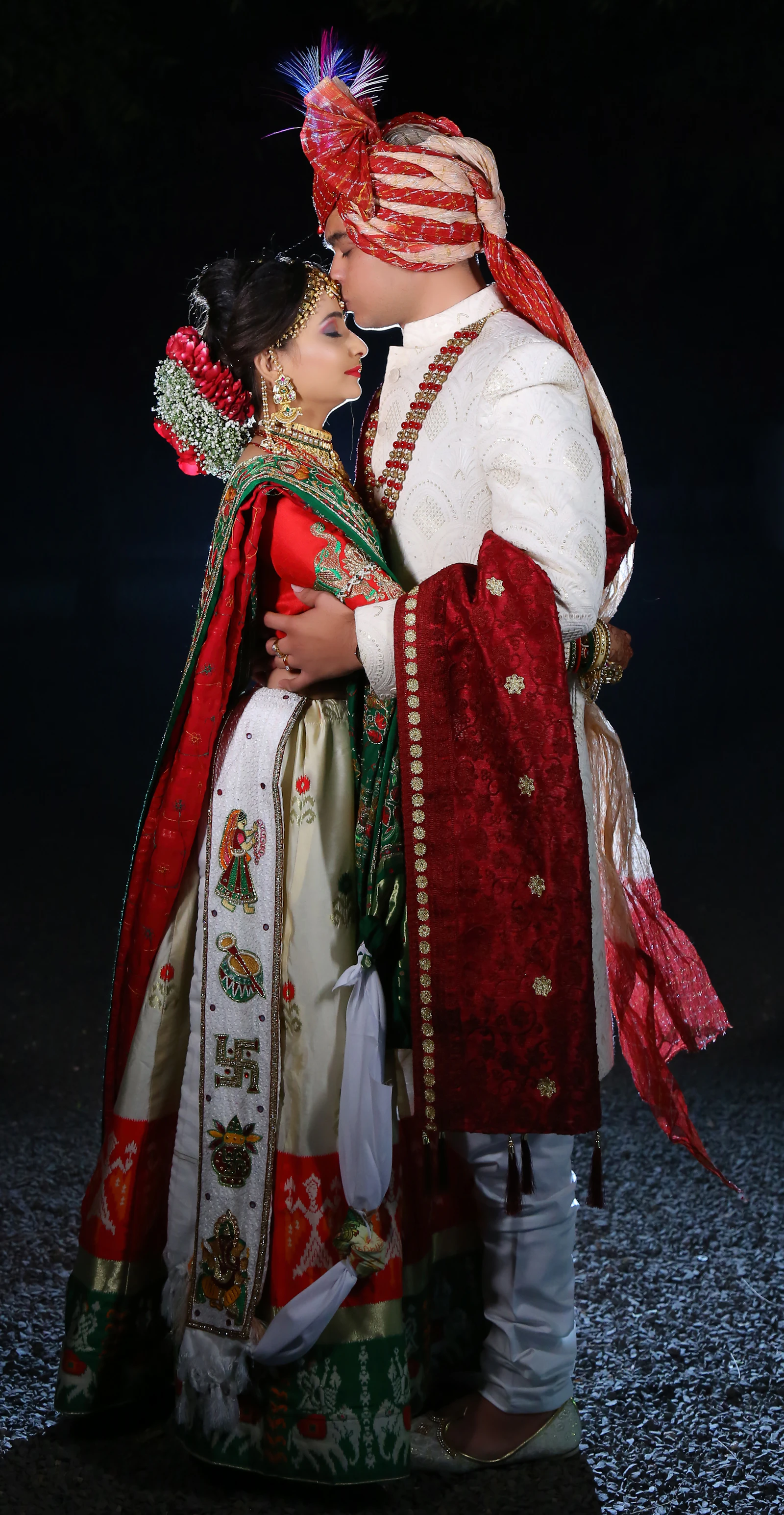 A groom in a white sherwani kissing his bride's forehead, photographed by Ira