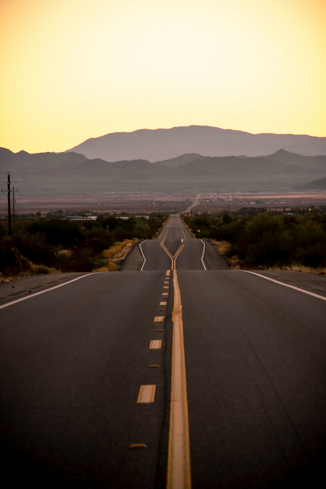 gray concrete road near green grass field during daytime