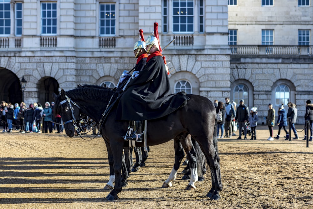 man in black and white coat riding black horse during daytime