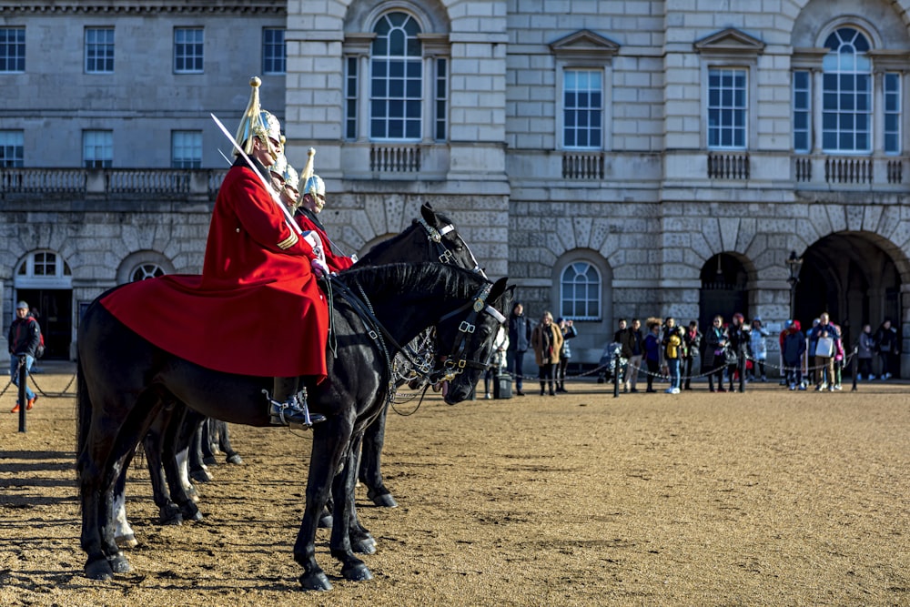 uomo in camicia a maniche lunghe rossa e bianca che cavalca il cavallo nero durante il giorno