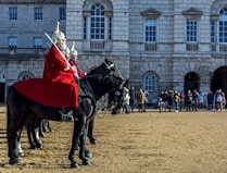 man in red and white long sleeve shirt riding black horse during daytime