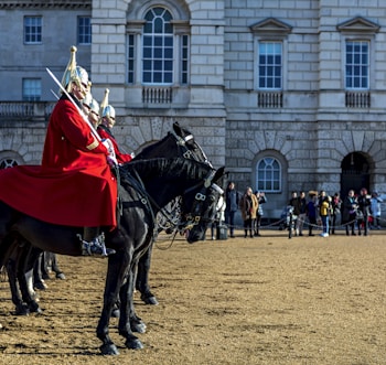 man in red and white long sleeve shirt riding black horse during daytime