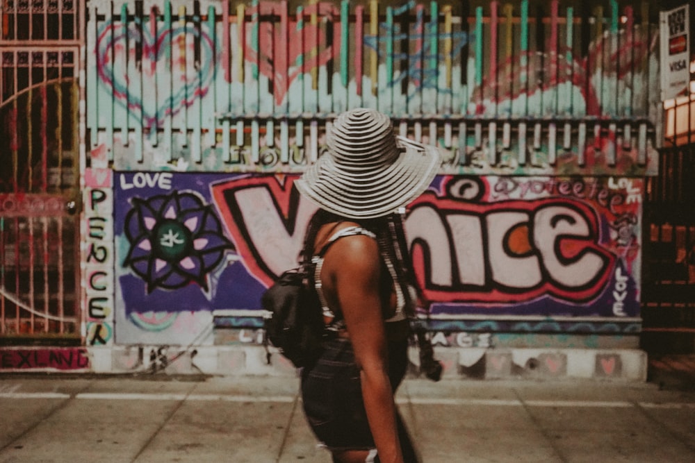 woman in black and white stripe hat standing near graffiti wall during daytime
