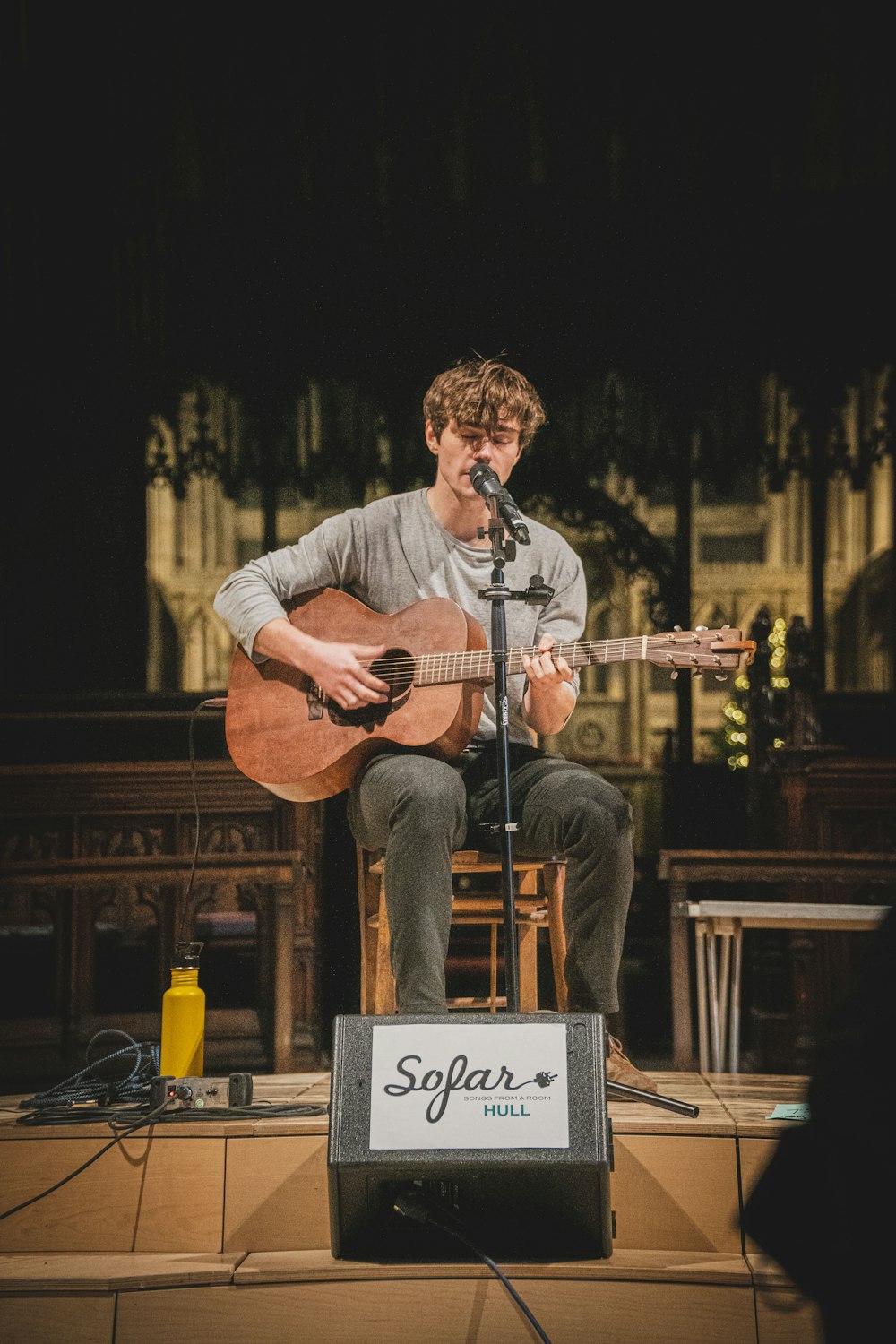 man in gray long sleeve shirt playing guitar