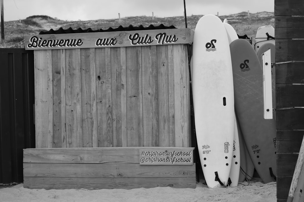 Graustufenfoto von Surfbrett auf Holzzaun