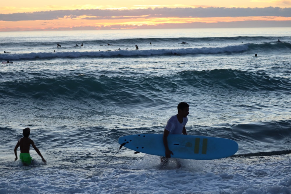 man in white shirt holding white surfboard on beach during daytime