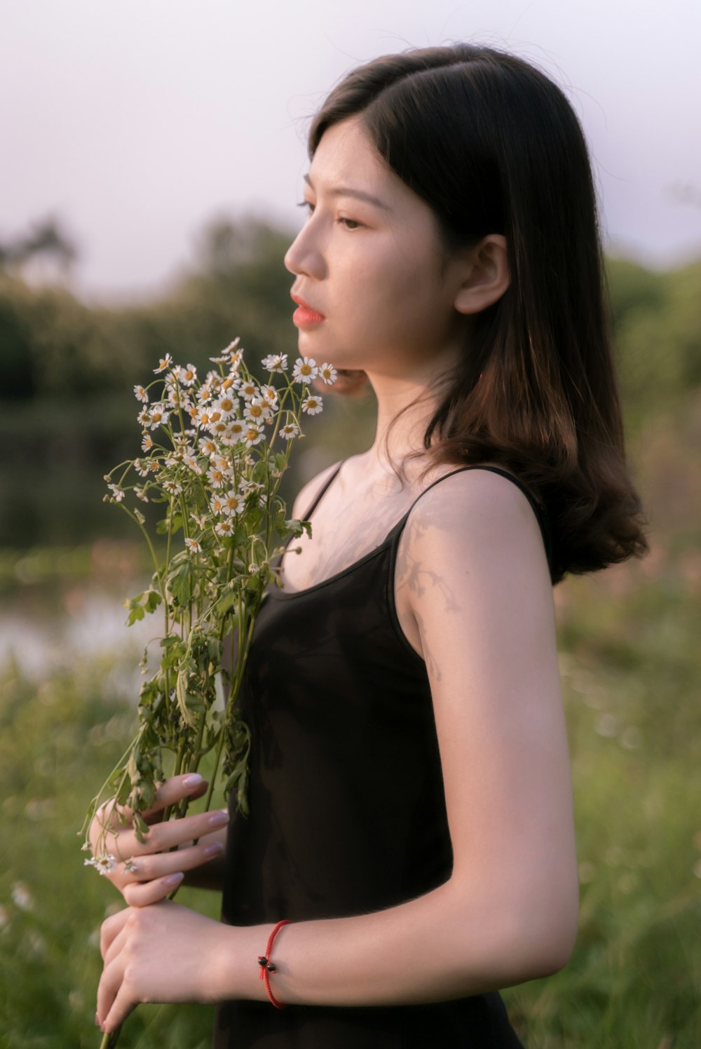 woman in black tank top holding white flowers