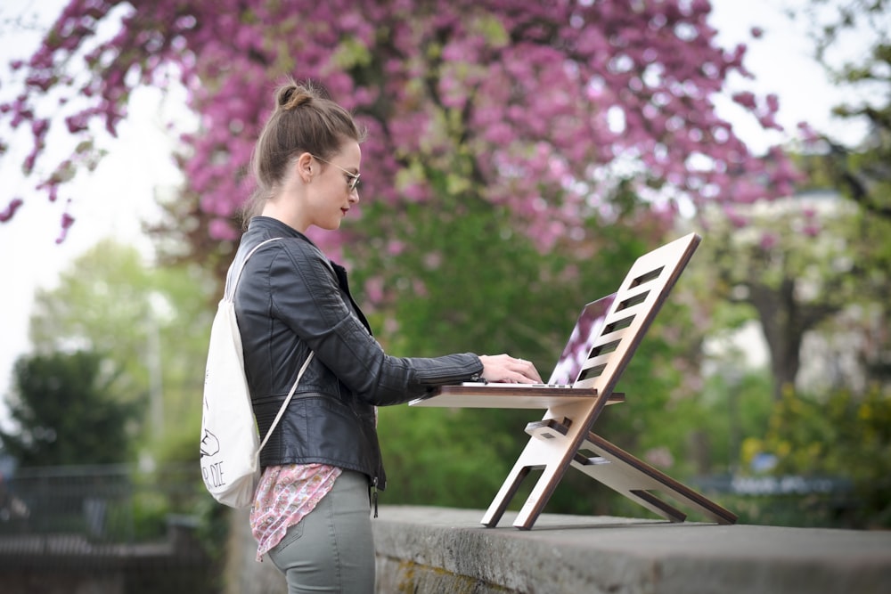 girl in black jacket and pink pants standing on white chair