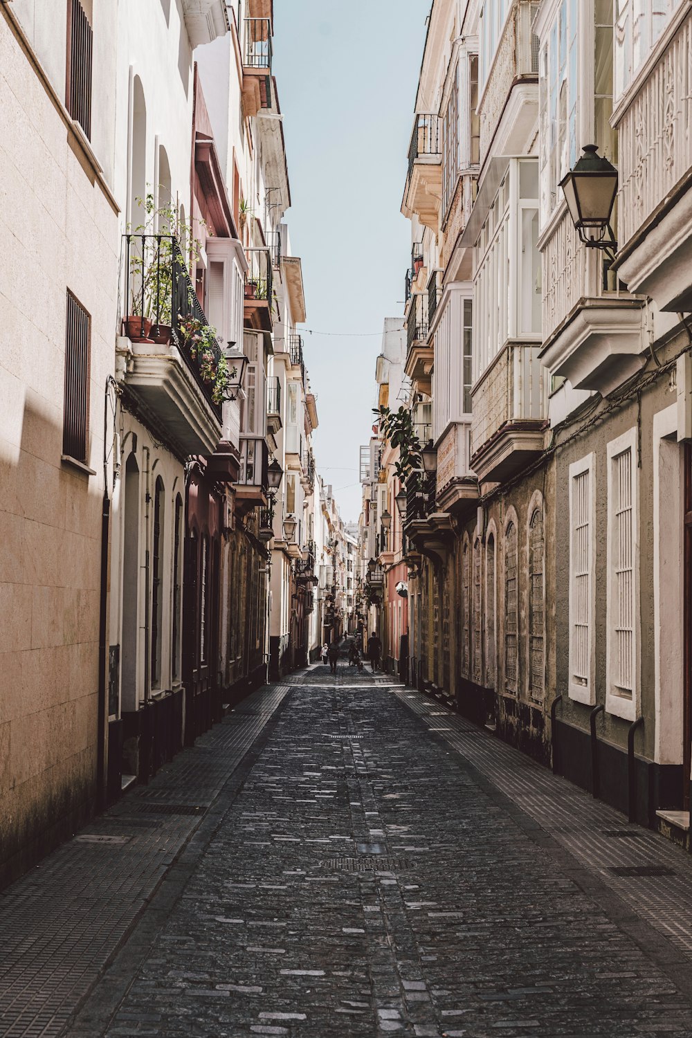 empty street between brown concrete buildings during daytime