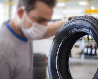 man in white shirt holding black tire