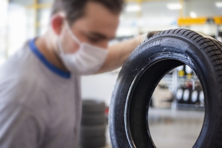 man in white shirt holding black tire