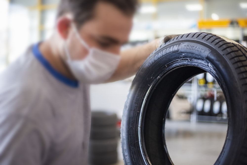 man in white shirt holding black tire