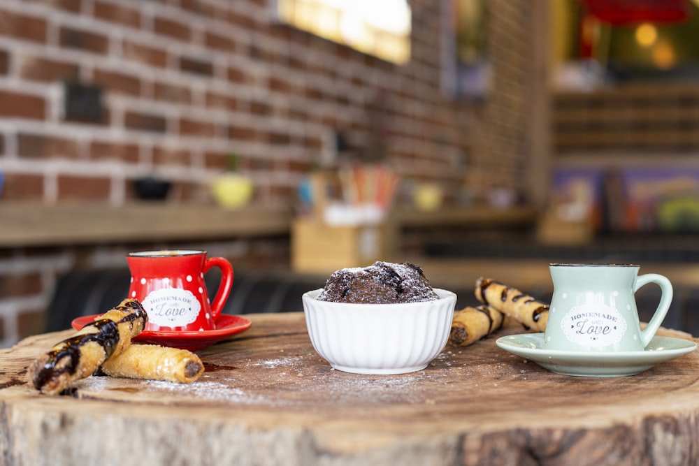 red ceramic mug beside white and red ceramic mug on brown wooden table