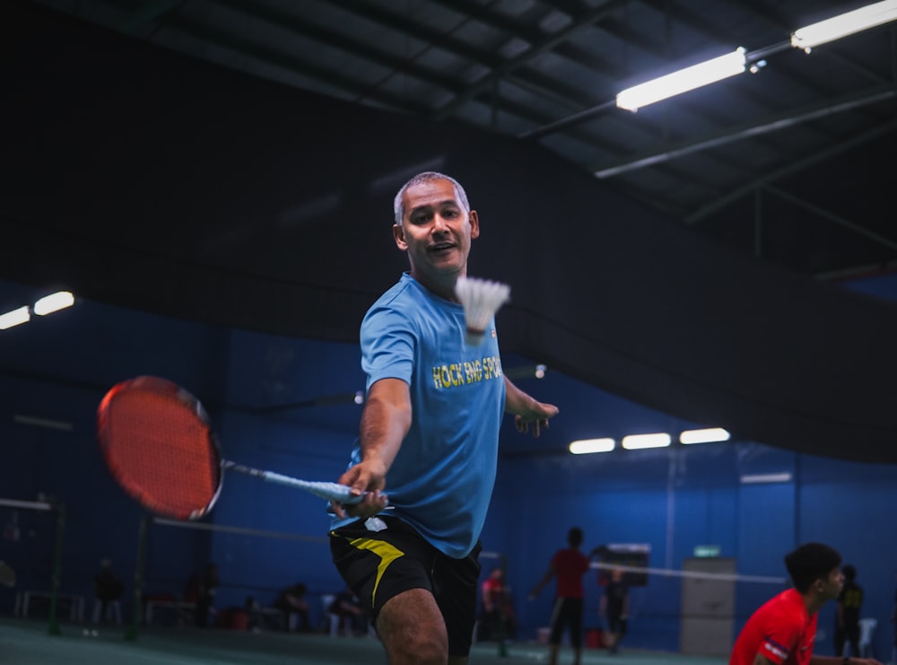 man in blue crew neck t-shirt and black shorts holding red basketball