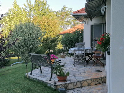 A cozy backyard patio with stone flooring and comfortable seating surrounded by lush greenery.