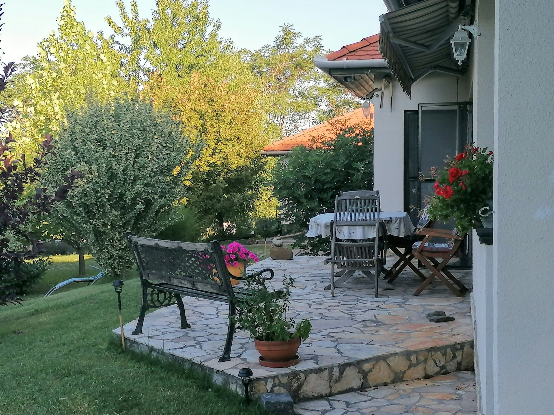 A freshly completed garden patio with natural stone paving surrounded by lush greenery and subtle outdoor lighting in an Irish backyard.