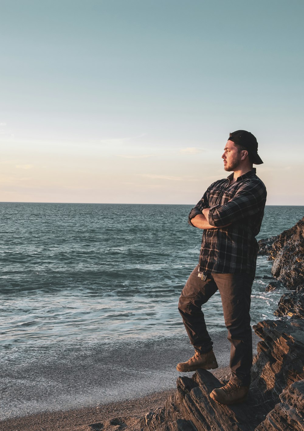 man in black and white plaid dress shirt and brown pants standing on rock formation near near on near on