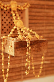 gold and white beaded necklace on brown wooden box