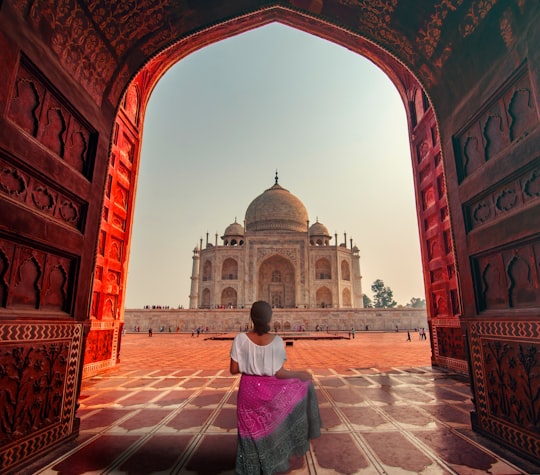 woman in white and pink dress standing on red and white concrete building during daytime in Taj Mahal India
