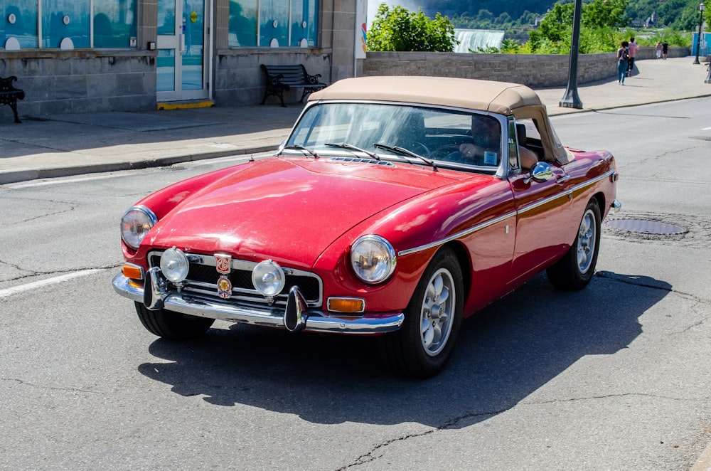 red classic car parked on sidewalk during daytime