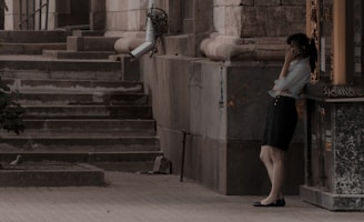 woman in white shirt and black skirt standing on gray concrete staircase