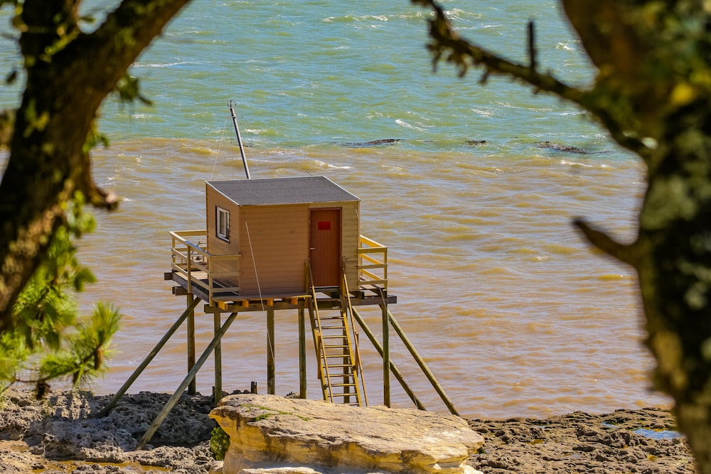 brown wooden lifeguard house on beach shore during daytime