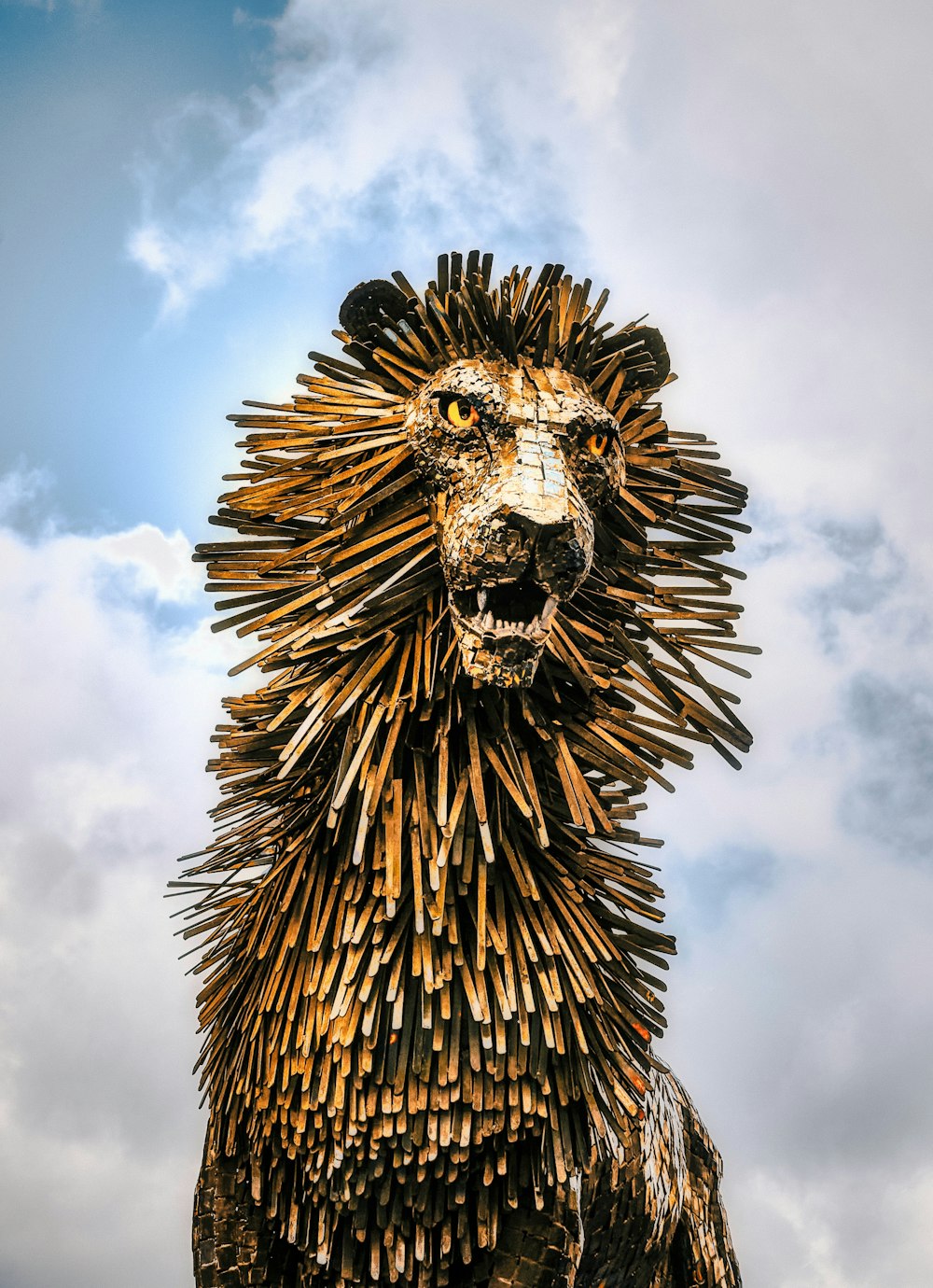 estatua de cabeza de león dorada y negra bajo nubes blancas y cielo azul durante el día