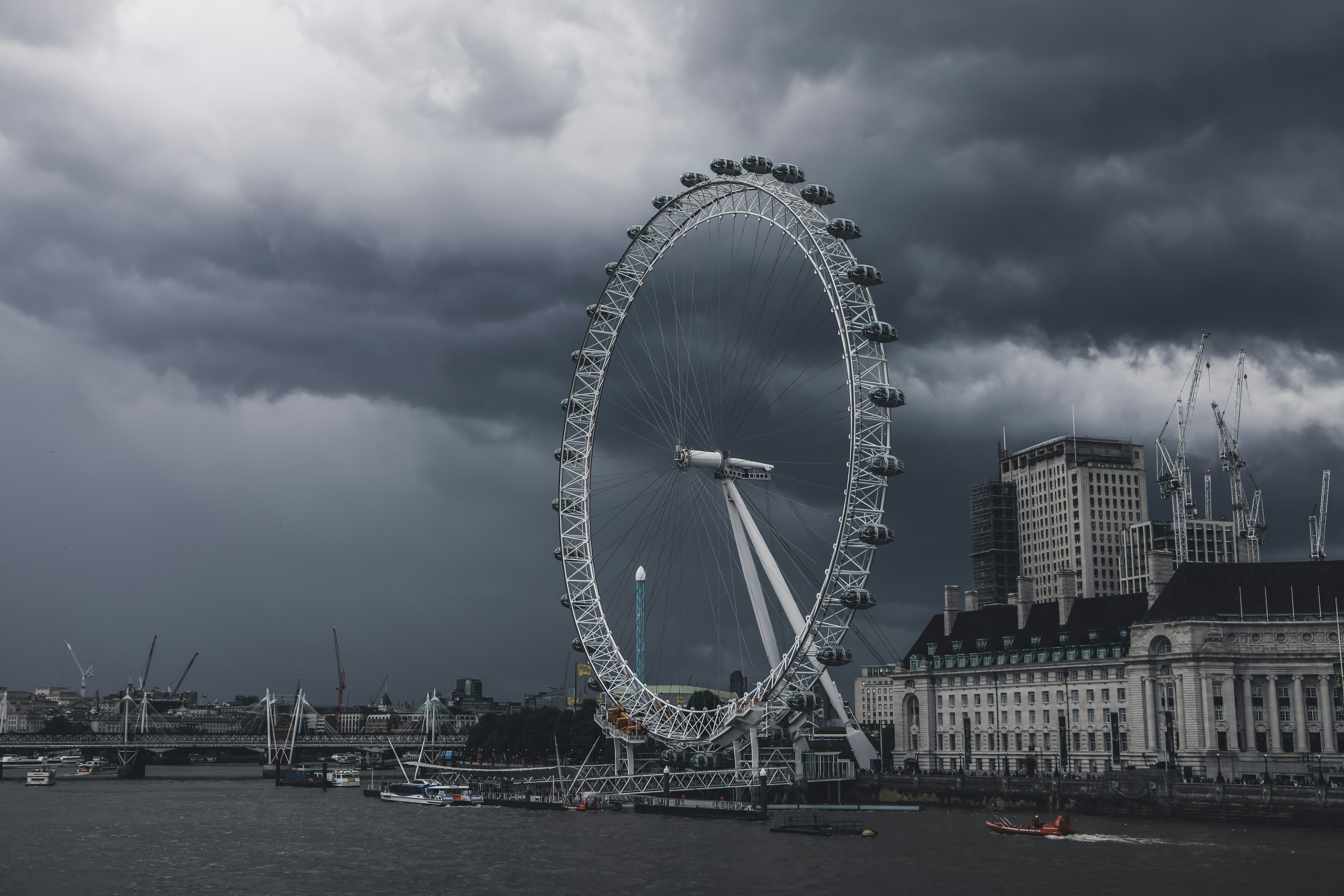 ferris wheel near city buildings under cloudy sky during daytime