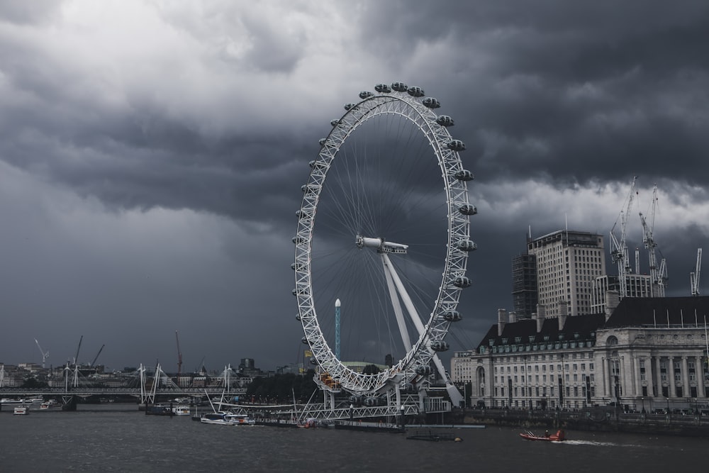 ferris wheel near city buildings under cloudy sky during daytime