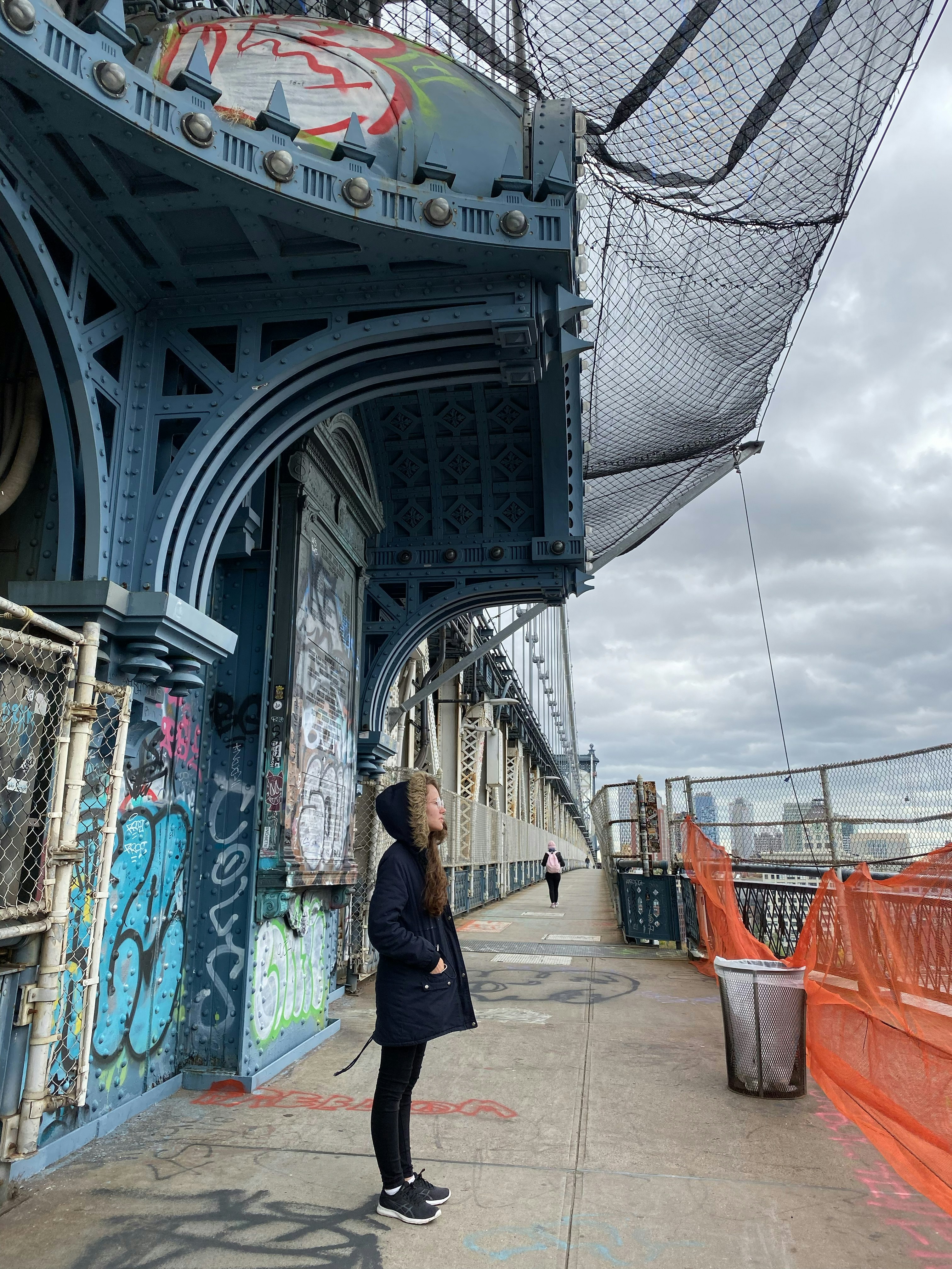 woman in black jacket walking on bridge during daytime