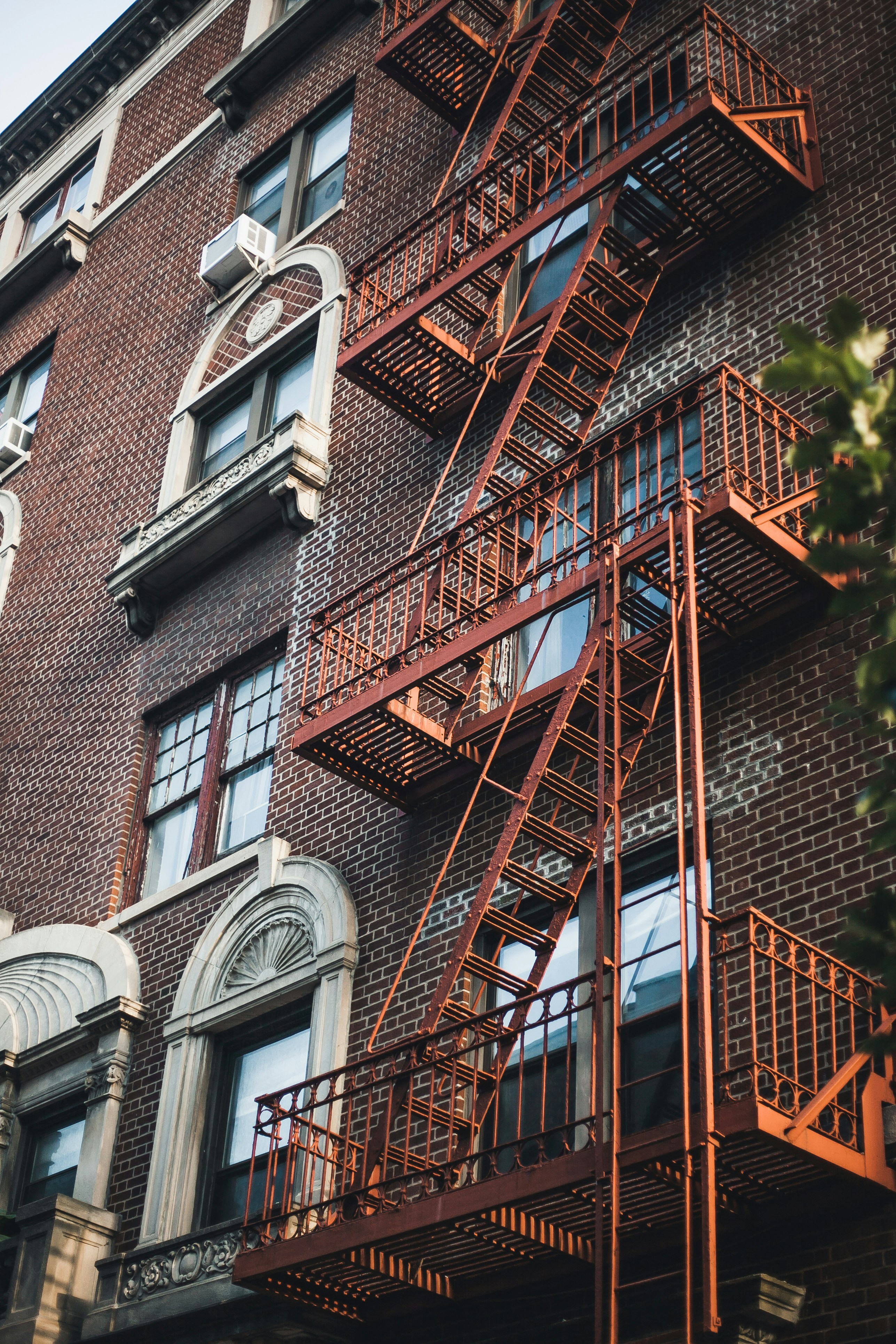 brown brick building with red metal window grills