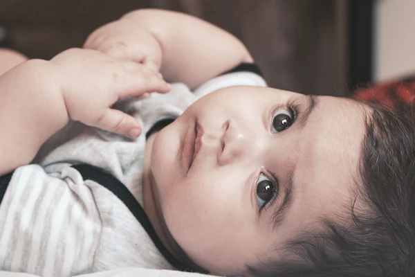 A baby lying down, looking up with wide eyes