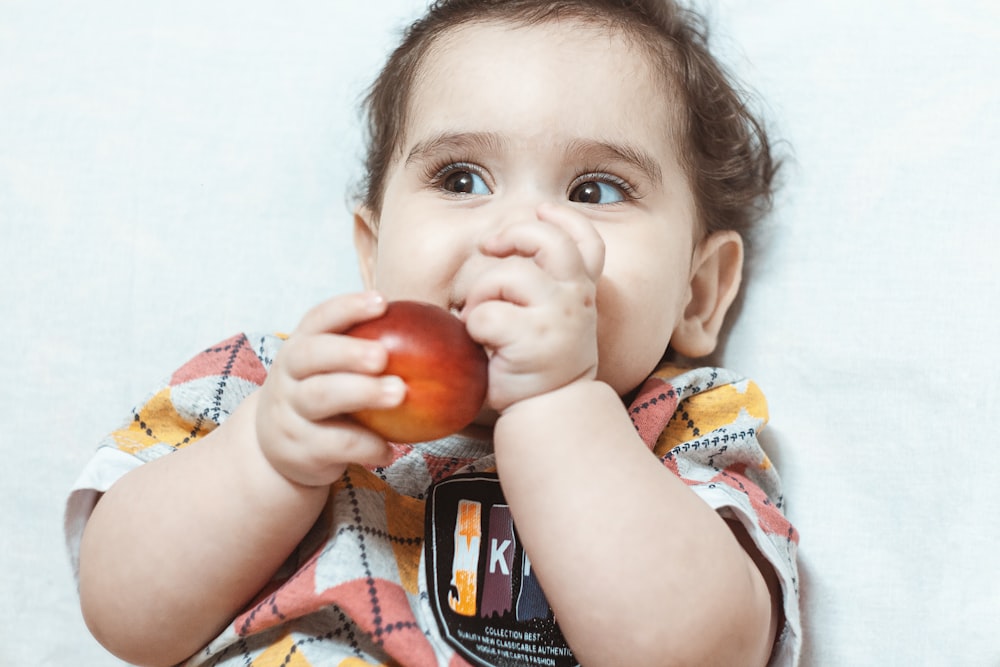 girl in white and red stripe shirt holding red apple