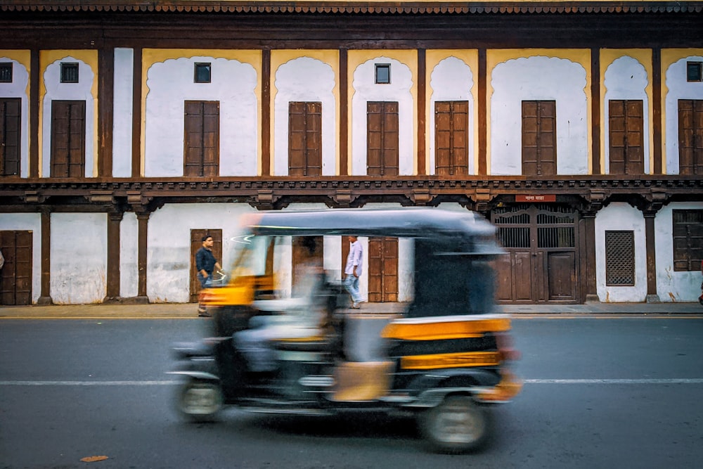 man in yellow jacket riding yellow and black auto rickshaw on road during daytime