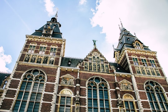 brown concrete building under white clouds during daytime in Rijksmuseum Netherlands