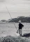 man in black jacket and white helmet fishing on sea during daytime