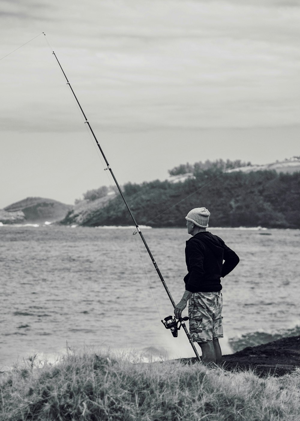 Hombre con chaqueta negra y casco blanco pescando en el mar durante el día