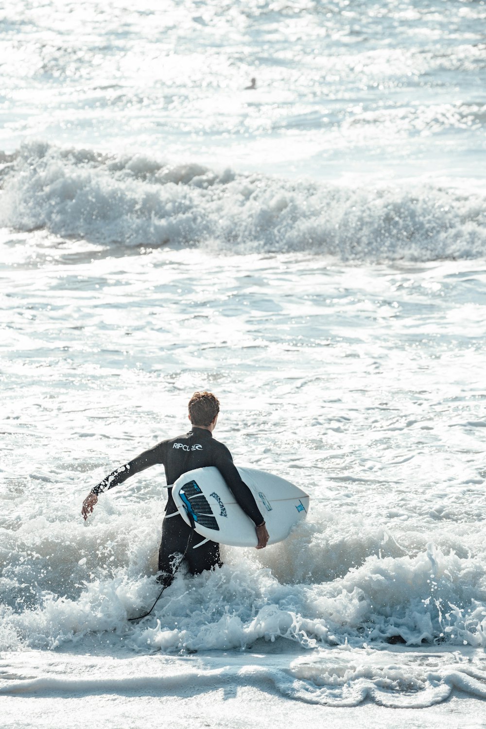 검은 잠수복을 입은 남자가 낮에 바다 파도에 서핑을 하고 있다