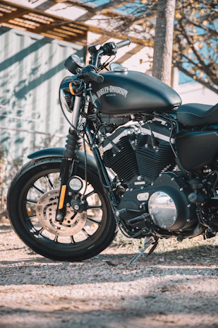 Close-up of a Harley Davidson motorcycle parked outside the shop in morning light.