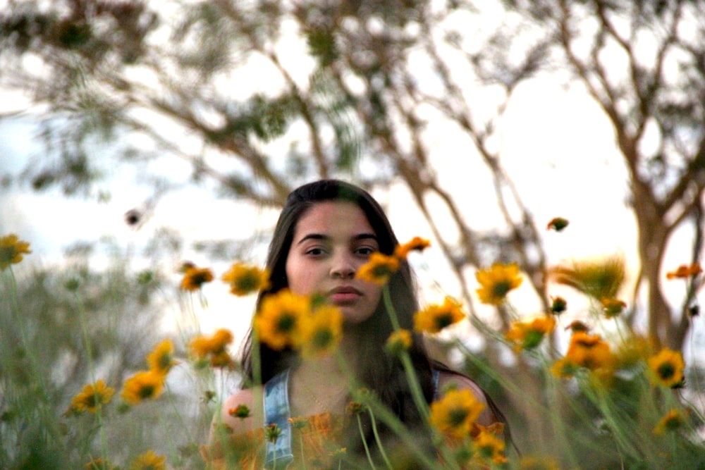 woman in blue and white floral dress standing on yellow flower field during daytime