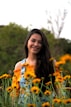 woman in blue and white floral tank top standing on yellow flower field during daytime