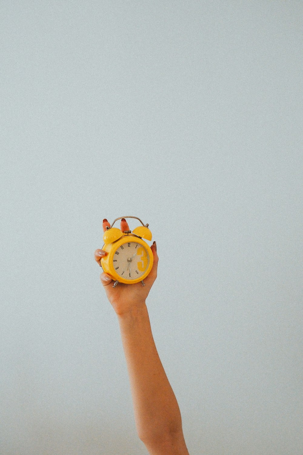 personne tenant une montre analogique jaune et blanche