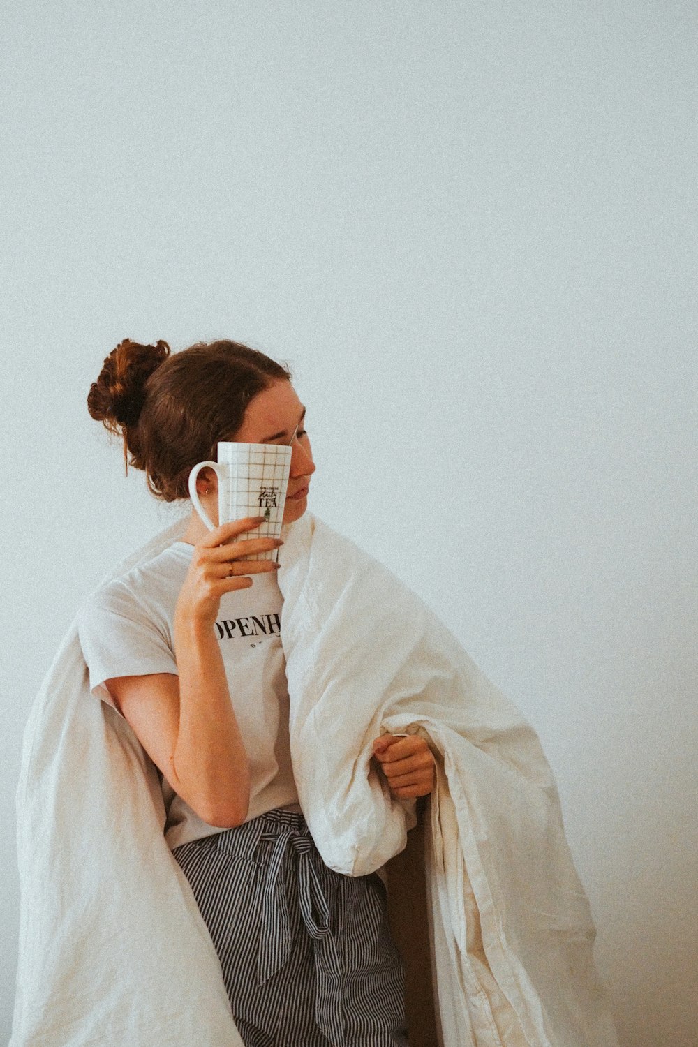 woman in white robe holding white ceramic mug