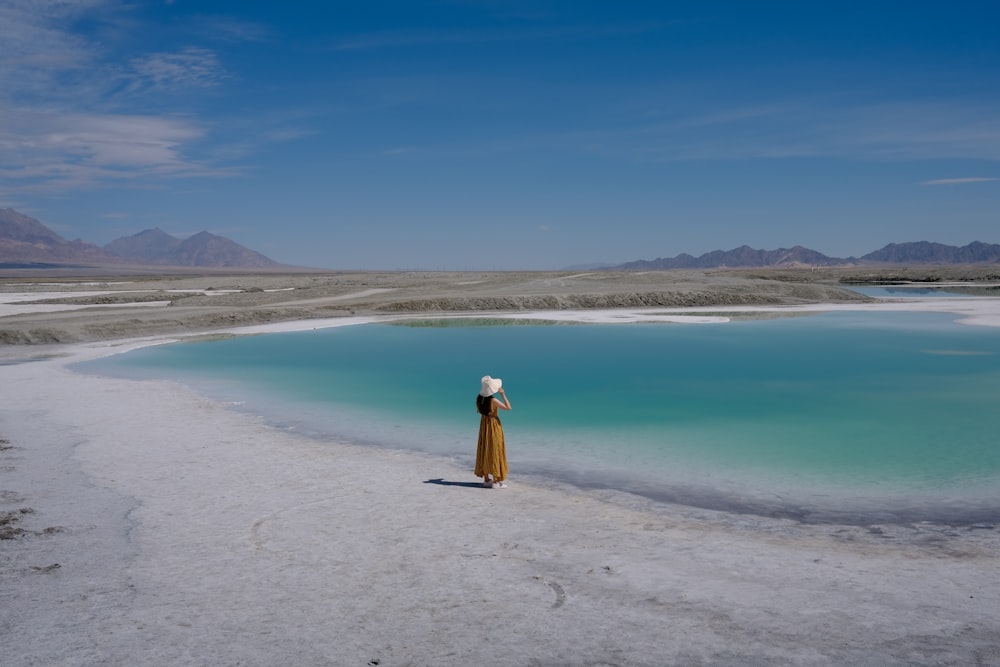 woman in yellow dress standing on beach during daytime