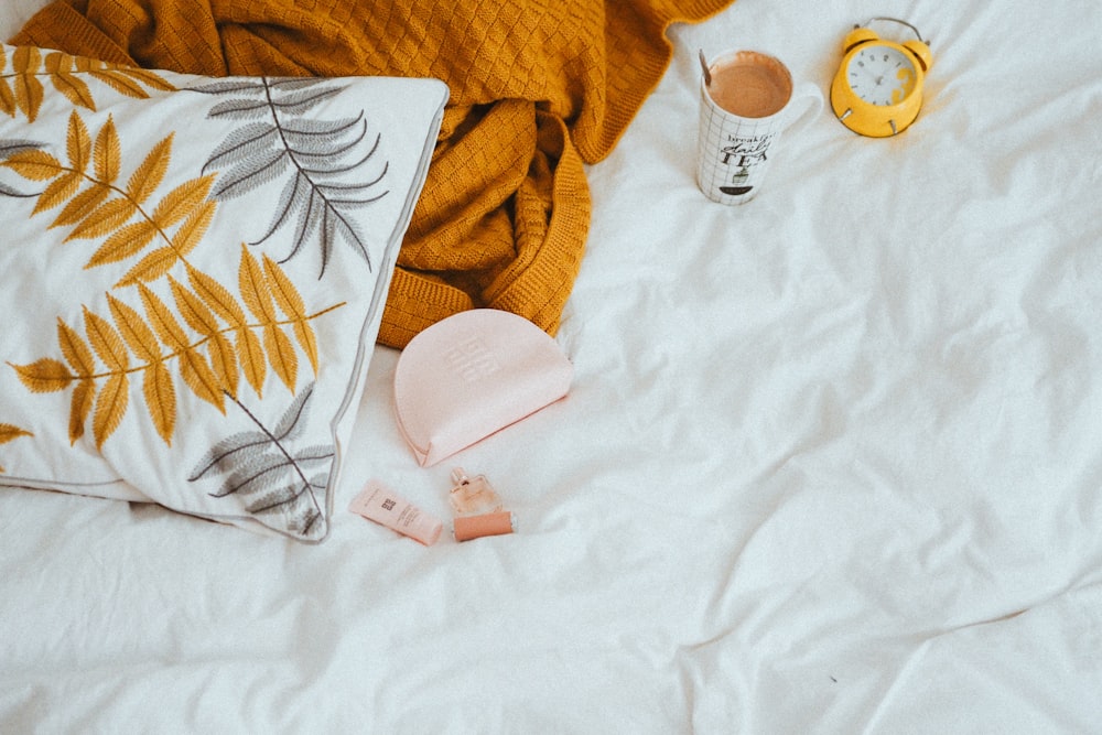 a white bed topped with pillows and a yellow blanket