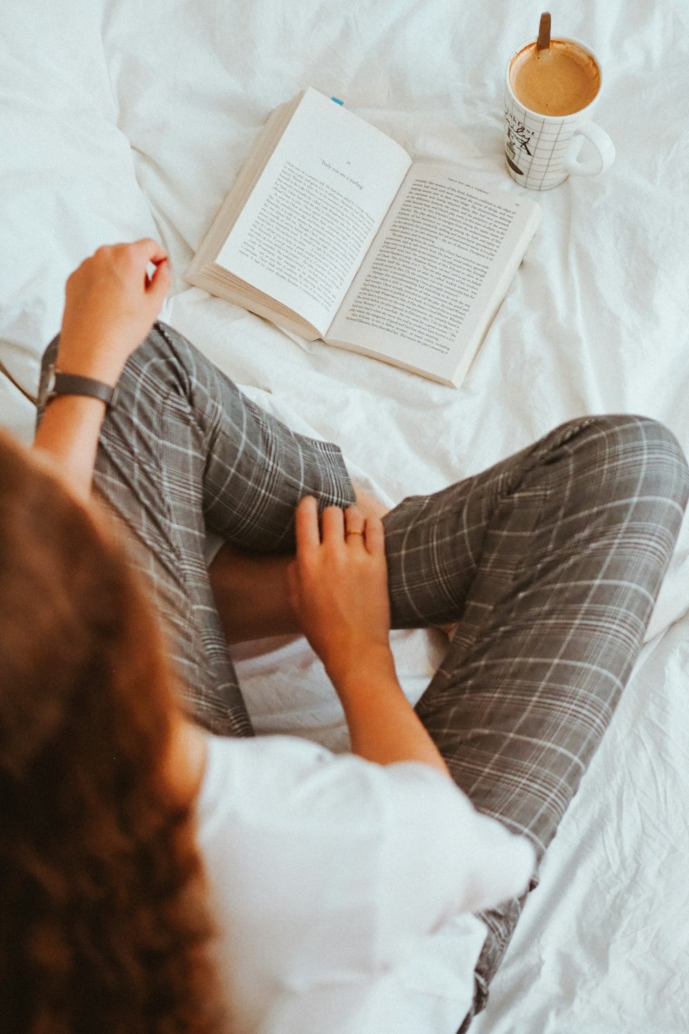 person in white shirt and gray pants lying on bed