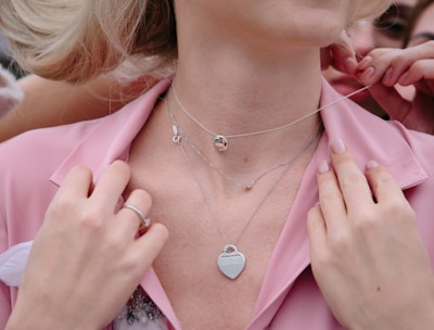 woman in pink blazer wearing silver heart pendant necklace